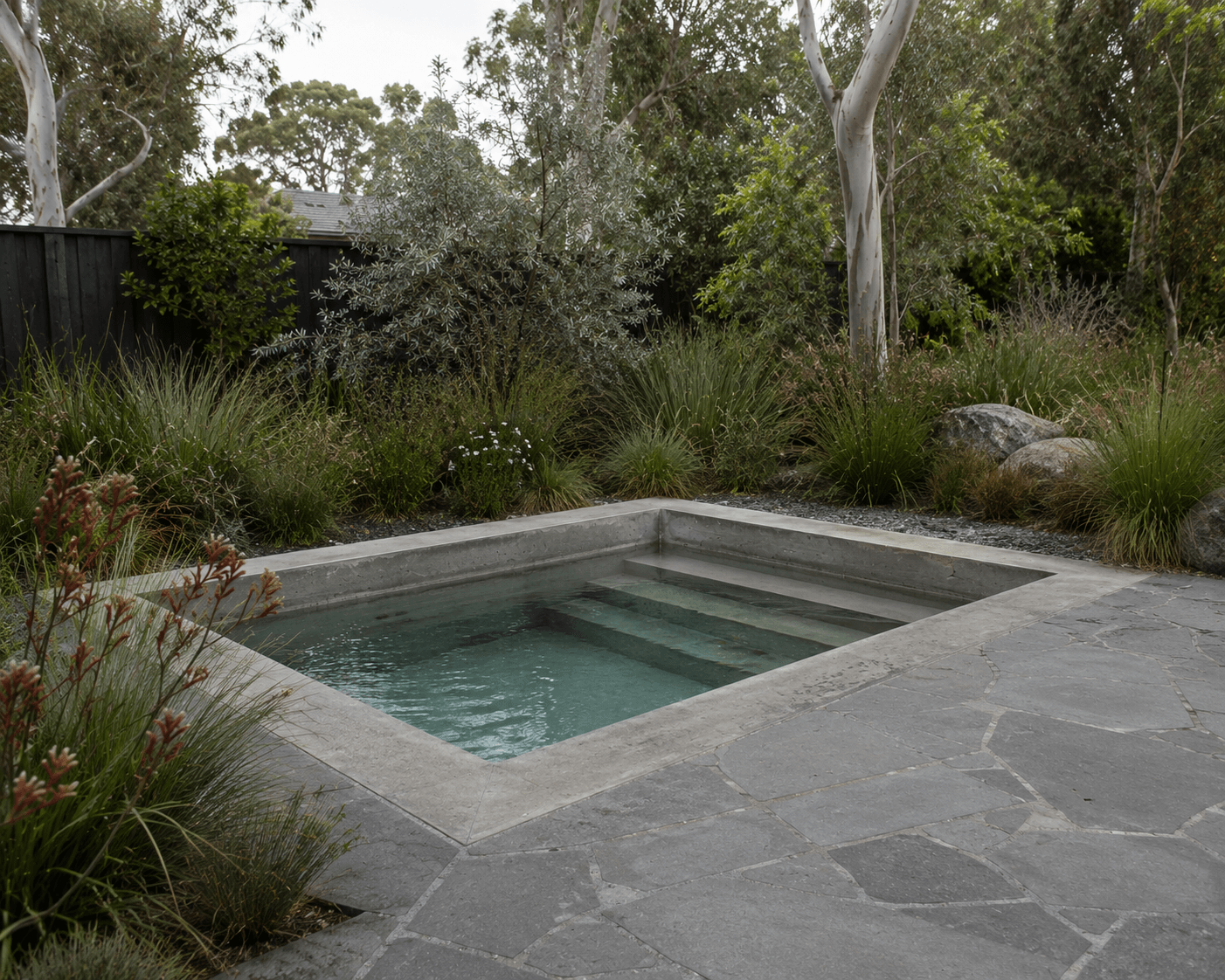 Concrete Spa surrounded by Melbourne landscaping with trees and grasses.